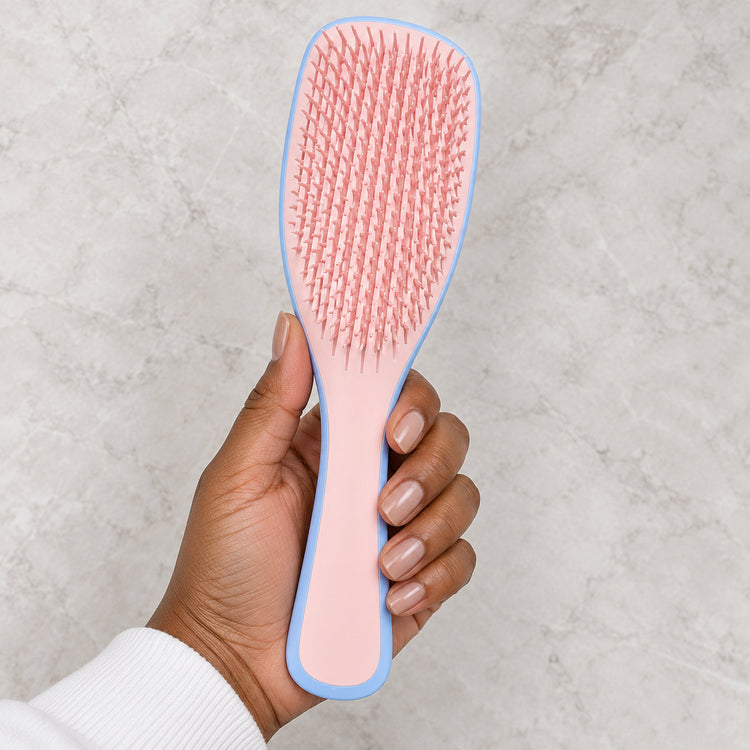 Hand holding the pink blue Knotty Brush detangling hair brush to show its size