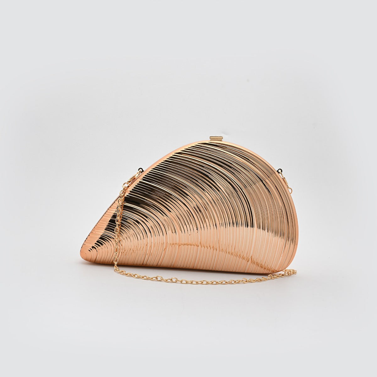 Champagne rose gold ribbed shell acrylic clutch purse, side view on a light gray background