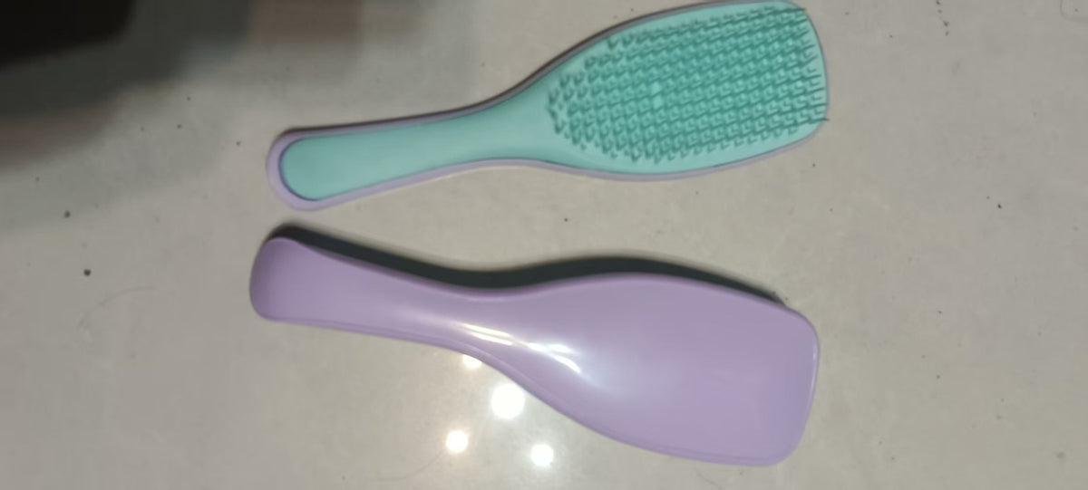 Mint green Knotty Brush detangling hair brush beside a purple brush
