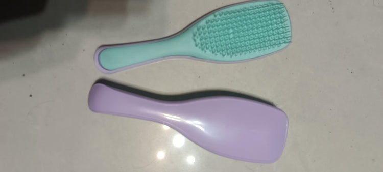 Mint green Knotty Brush detangling hair brush beside a purple brush