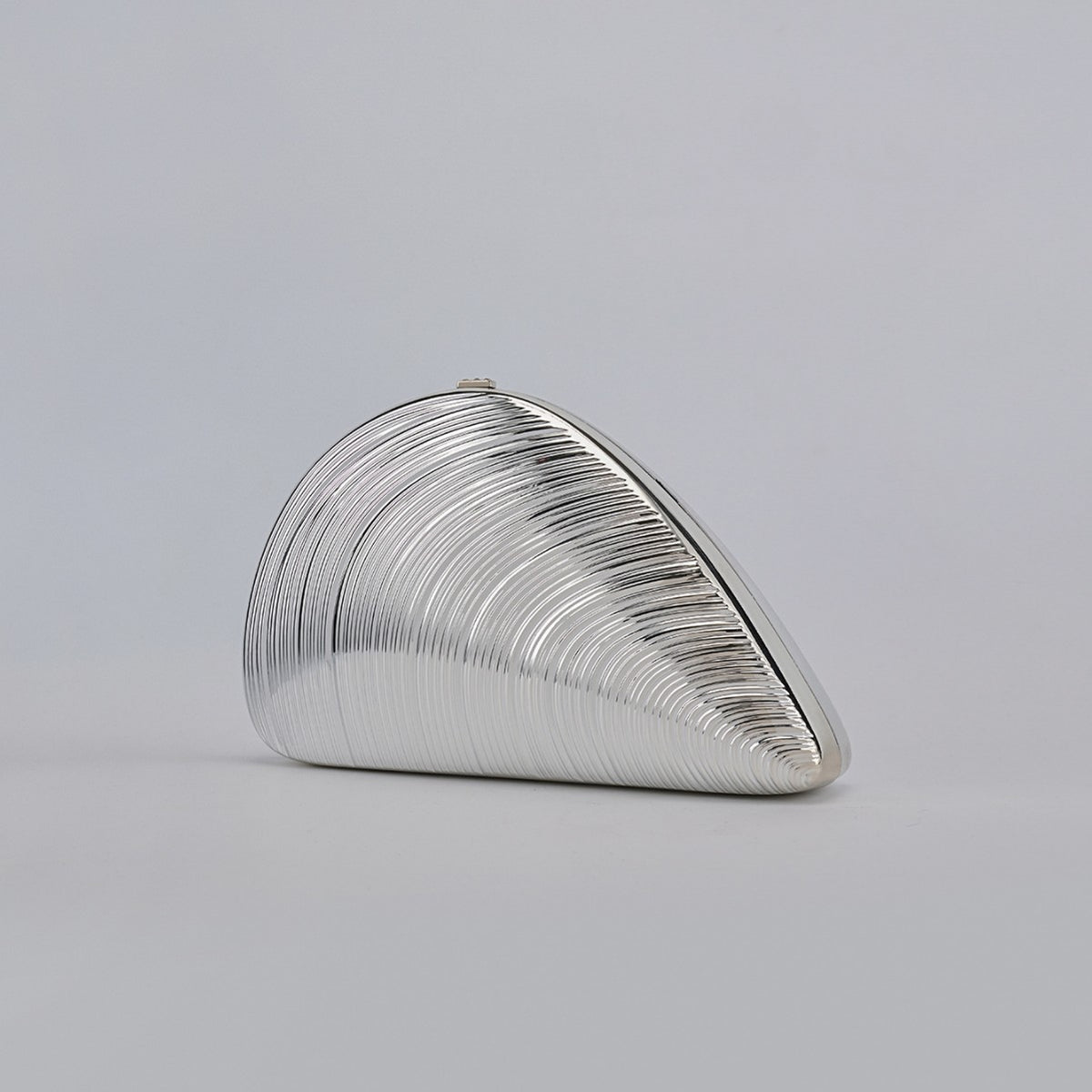 Silver ribbed shell acrylic clutch purse, side view on a light gray background